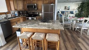 Una cocina moderna con armarios de madera, electrodomésticos de acero inoxidable, encimera de granito y una isla central con taburetes de bar.