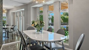 A modern dining area with a marble table, black chairs, and a vase of flowers. - An Extra Hour of Sunshine, Southern California Desert (Rancho Mirage)
