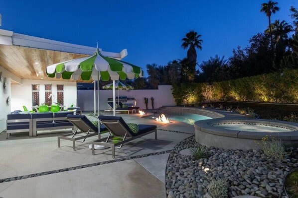 A poolside area with lounge chairs, a covered seating area, and a hot tub.