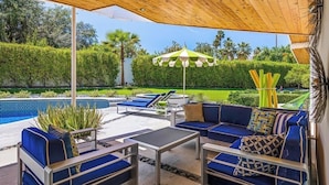 An outdoor patio with a pool, lounge chairs, and a covered seating area. - An Extra Hour of Sunshine, Southern California Desert (Rancho Mirage)