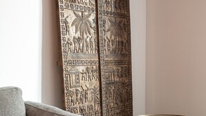 A room with a grey sofa, a macrame throw, a round wooden table, and a large decorative panel with intricate carvings. - LaSuitedu12 - Aprtement for 2 people view of the Old Prison (Annecy)