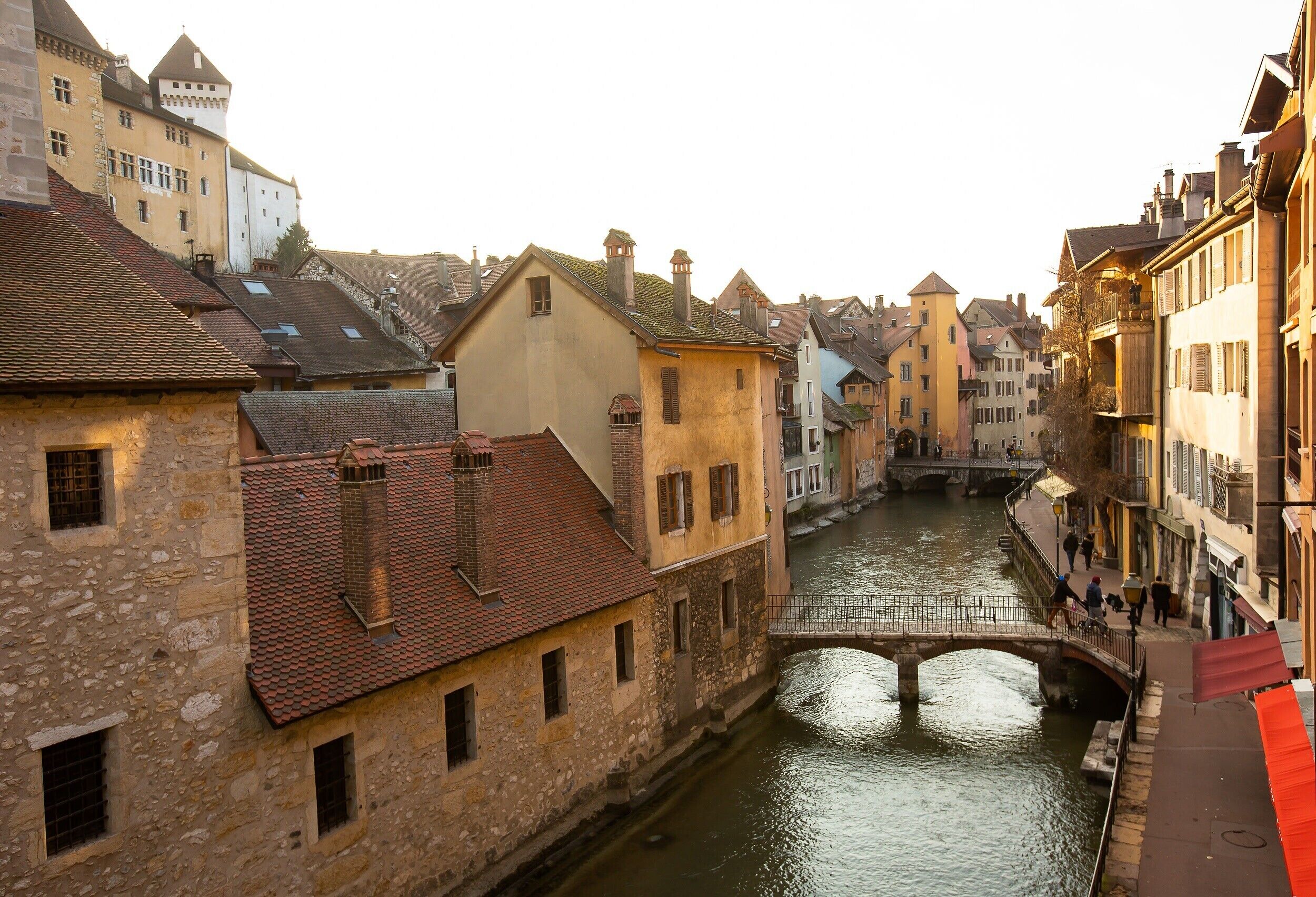 A narrow waterway flanked by historic buildings with stone facades and red-tiled roofs.