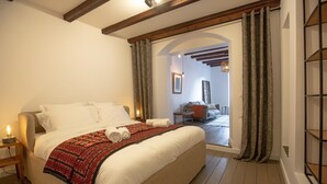 A bedroom with a large bed, a nightstand, and a view of a living area through an open door. - LaSuitedu12 - Aprtement for 2 people view of the Old Prison (Annecy)