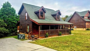 A log cabin with a porch, a covered front porch area, and a small front yard.