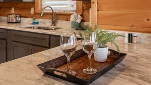 A kitchen with a marble countertop, two wine glasses on a tray, a potted plant, and a toaster.