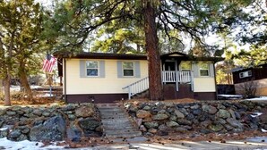 A single-story house with a stone wall and steps leading to a front door. - Hillside Cottage In The Pines With Great Views (Williams)