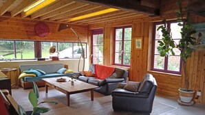A cozy cabin interior with wooden walls, a sofa, a coffee table, and a dining table.
