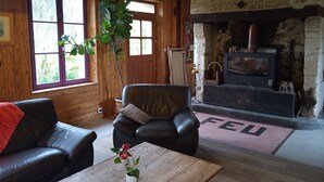 A cozy living room with a fireplace, leather sofas, and a wooden floor.