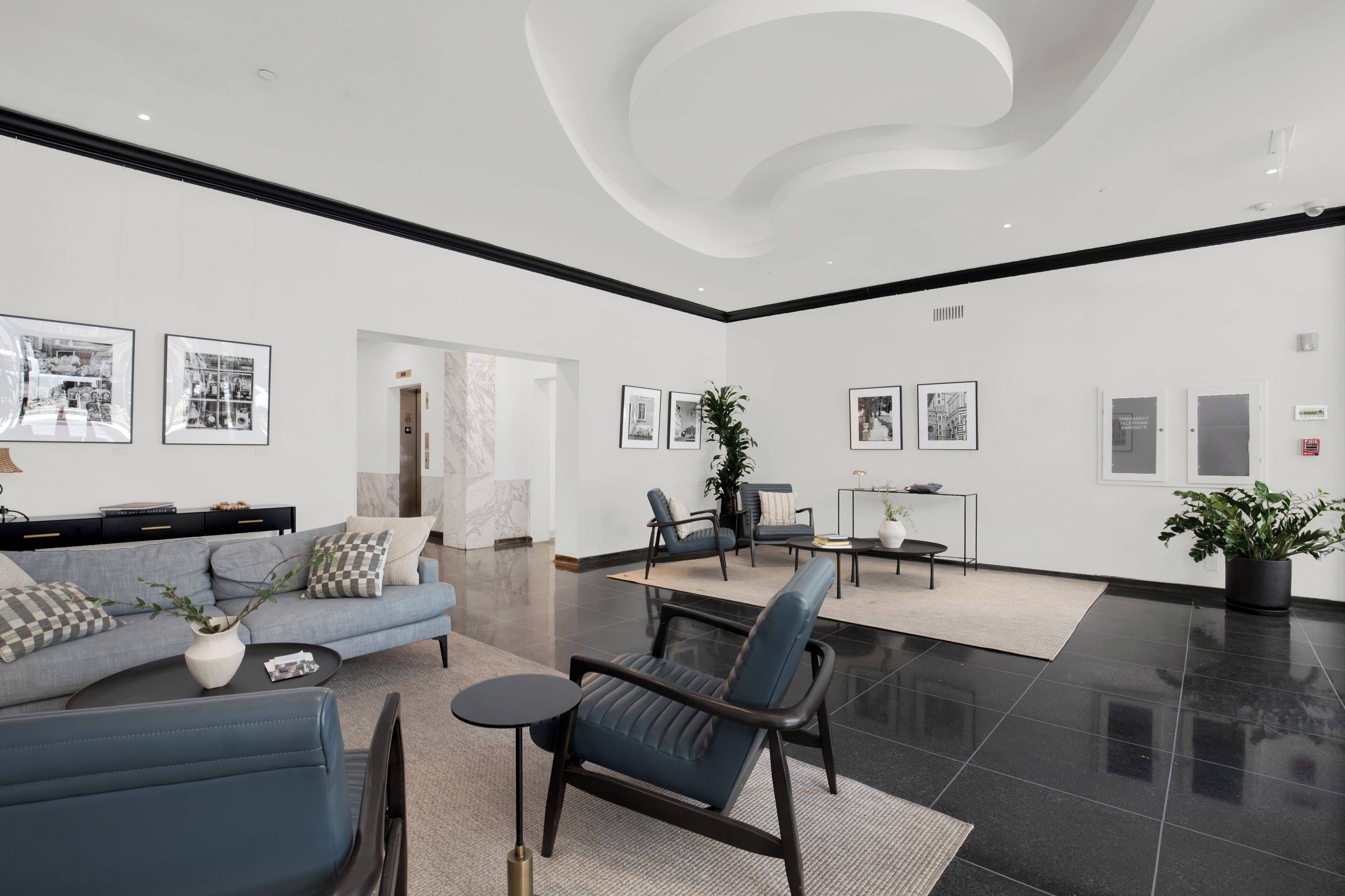 Eine großzügige Lobby mit modernem Design, ausgestattet mit einer Sitzecke mit Sofas und Sesseln, einem Couchtisch und einer Topfpflanze.