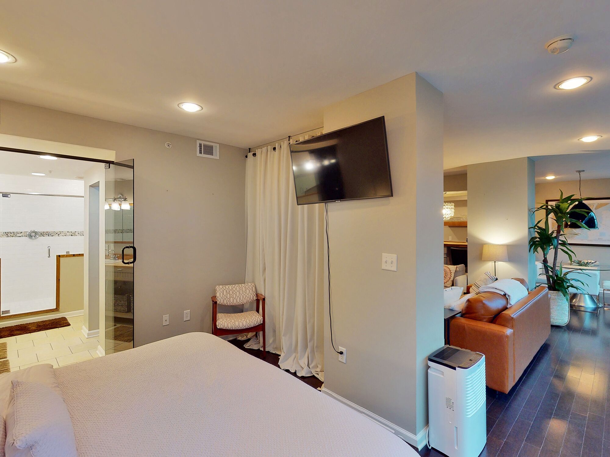 A hotel room with a bed, a TV, a chair, a sofa, and a heater.