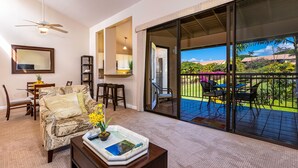 Un salon avec un canapé, une table basse et un balcon donnant sur un jardin et des immeubles.