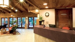Un espace d’accueil doté d’un plafond en bois, d’un comptoir de réception, d’une horloge et d’une grande fenêtre donnant sur un paysage verdoyant.