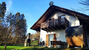 Ein rustikales Chalet mit Balkon, Schornstein und Sitzgelegenheit im Freien.