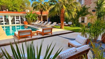 A pool area with lounge chairs and a stone building in the background.