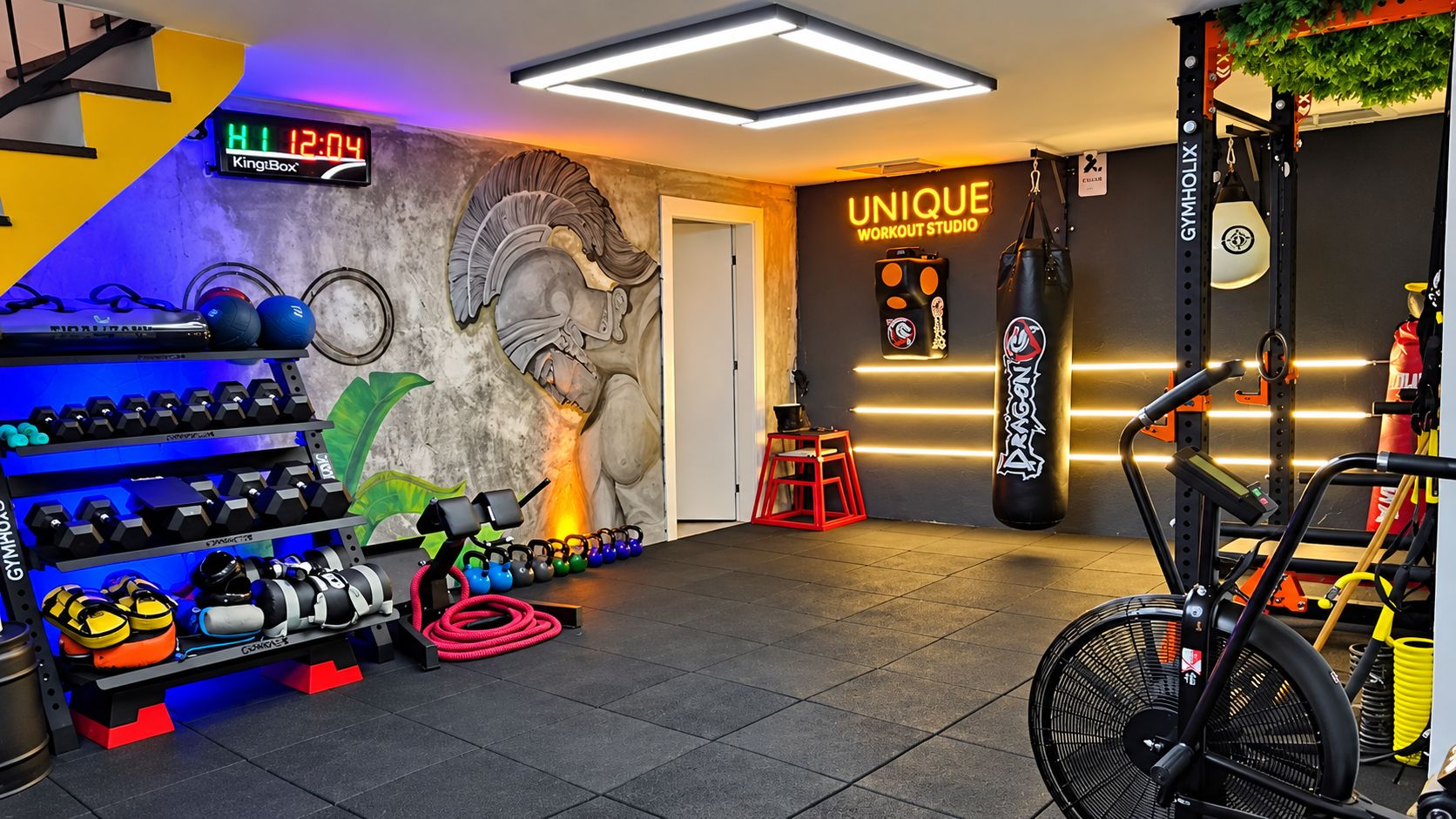 A gym with a digital clock, a mural, a punching bag, and various exercise equipment.