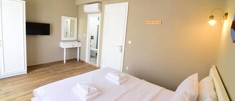 A hotel room with a bed, a bedside table, a mirror, and a wall-mounted TV.