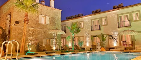 A poolside area with lounge chairs, umbrellas, and a pool.
