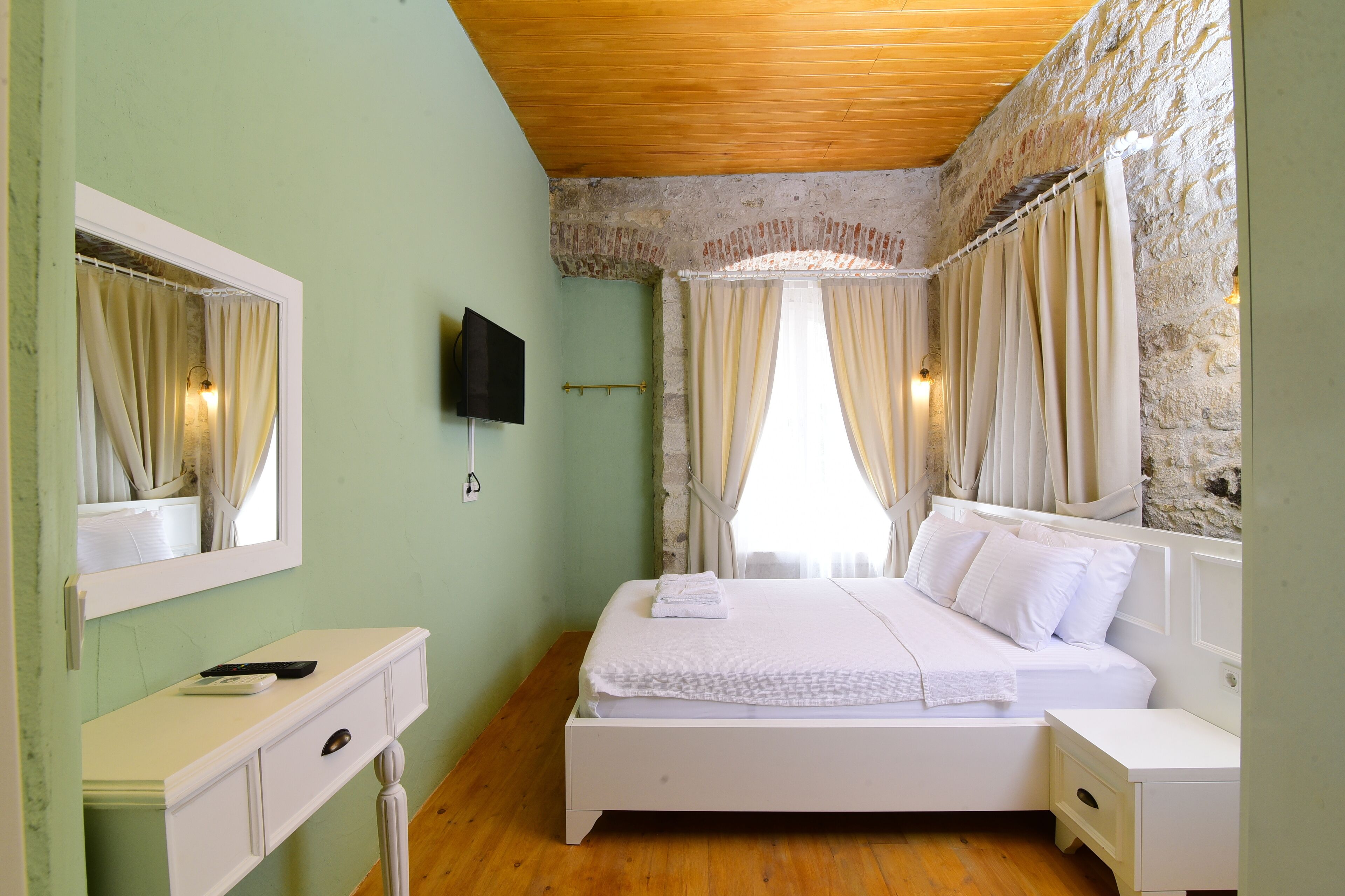 A bedroom with a bed, a TV, a bedside table, and a dresser.