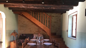 Zona pranzo con tavolo in legno apparecchiato per quattro persone, una scala e vista all'esterno.