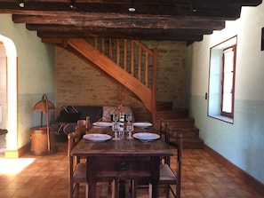 Cozy dining area with a rustic table for four, surrounded by a wooden staircase and a window.