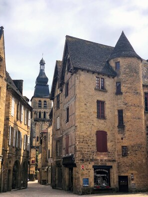 Una estrecha calle flanqueada por edificios históricos de piedra, entre ellos un edificio destacado con un letrero que dice "La Truffe du Perigord".