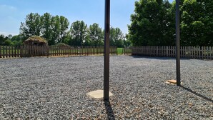 Un espace extérieur abrité, doté d’un sol en gravier, d’une clôture en bois et d’arbres en arrière-plan.