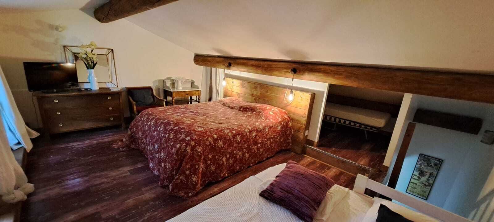 A bedroom with a bed, wooden dresser, and a desk.