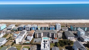 A coastal hotel with multiple buildings, a swimming pool, and a beach view. - Coastal Beach Condo (Carolina Beach)