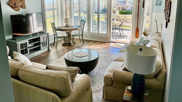 Een woonkamer met een televisie, bank, salontafel, en een eethoek met stoelen en een tafel.
