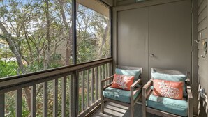 Ein Balkon mit zwei Holzstühlen, jeder mit Kissen und Zierkissen.