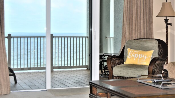 A room with a view of the sea, a chair with a cushion, a lamp, and a table with a tray. - "Sunrise Sonata" Direct Oceanfront Penthouse Stunning Sunrises • Holiday Promo (Palm Coast)
