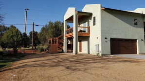 Un edificio de dos pisos con balcón, garaje y entrada de tierra.