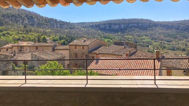 A balcony with a view of a village and mountains.