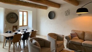 A dining area with a wooden table and chairs, a sofa, and a wall clock.