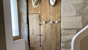 A wooden door with two hats hanging on hooks, a basket, and a stone wall.