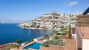 A coastal residential area with a view of the sea and a hill with houses.
