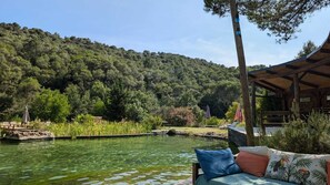 A serene riverside setting with a wooden deck, lounge chairs, and a covered seating area.