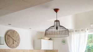 Una cocina funcional con comedor, un reloj y una lámpara colgante.