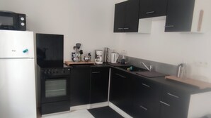 Eine moderne Küche mit schwarzen Schränken, einem weißen Kühlschrank, einem Herd und einer Mikrowelle.