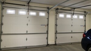 A double garage with two white doors, metal frames, and overhead lighting. - Bright new 2nd-floor space near Mayo Clinic & downtown (Rochester)