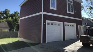 A two-story house with a dark brown exterior and white trim, featuring two garage doors and a visible garage door opener. - Bright new 2nd-floor space near Mayo Clinic & downtown (Rochester)