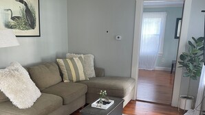 Ein Wohnzimmer mit einem Ecksofa, einem Couchtisch und einem gerahmten Gemälde von Wildtieren.