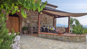 A stone building with a covered patio area, outdoor seating, and a view of the mountains.