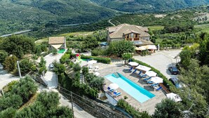 A villa with a swimming pool, surrounded by lush greenery and mountains.