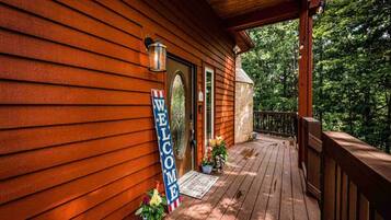 A wooden cabin with a porch, a welcome sign, and a mailbox.