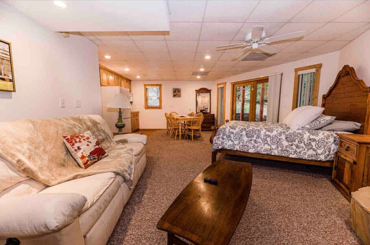 Une pièce confortable comprenant un lit, un canapé, une table basse en bois, une table à manger avec des chaises et un ventilateur de plafond.