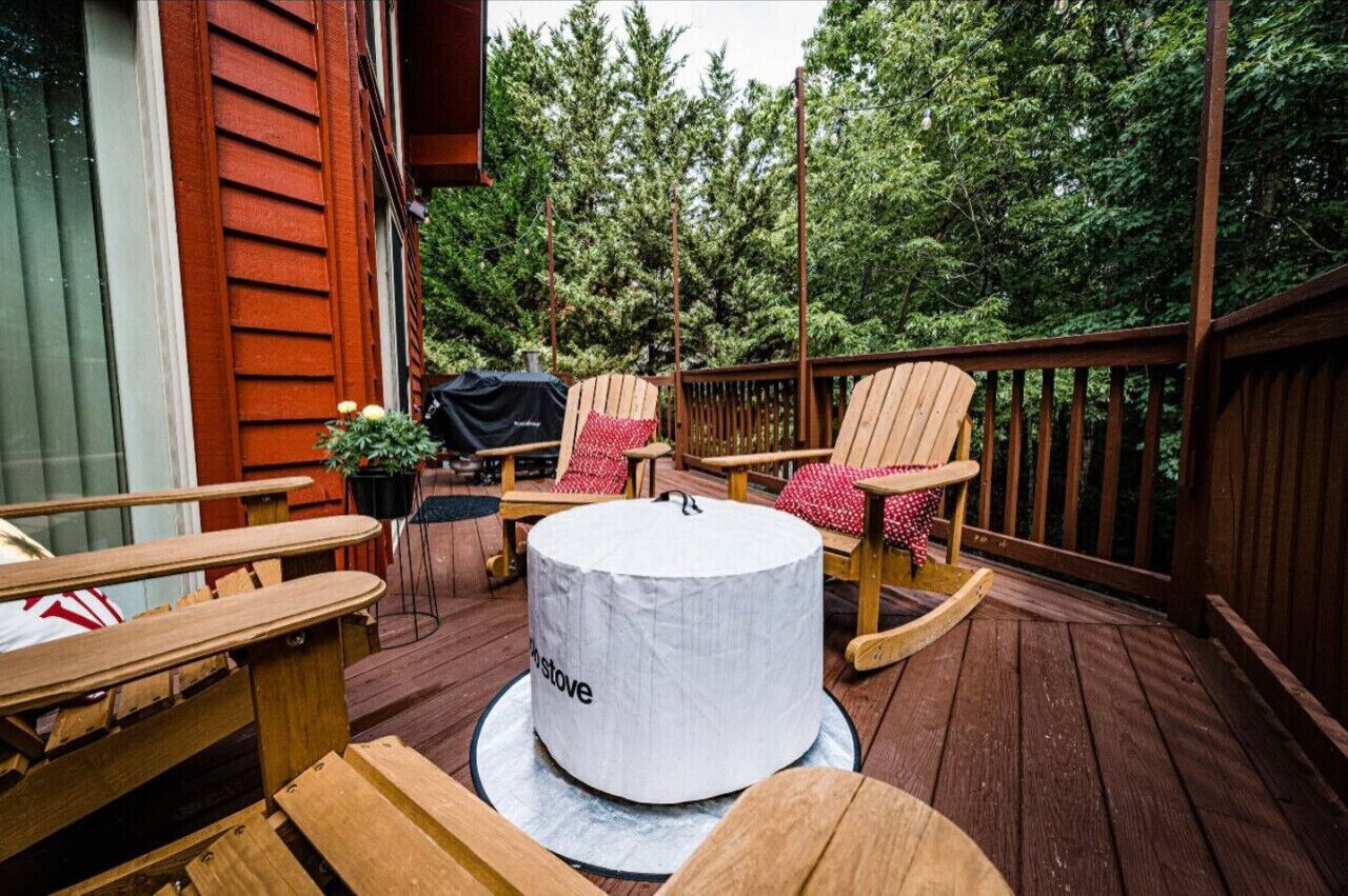 Une terrasse en bois aménagée avec du mobilier d’extérieur, notamment des chaises et une table, ainsi qu’un barbecue.