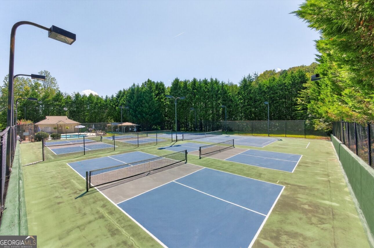 A tennis court complex with multiple courts, a covered seating area, and a street lamp.