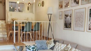 Una sala de estar moderna con una escalera, un comedor y obras de arte en las paredes.