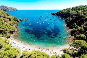 A coastal beach with clear turquoise waters, boats, and greenery. - House with sea and mountain views in Almadrava AV 36 (Rosas / Roses)